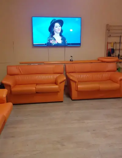 Una stanza comune della struttura, con televisione e divani arancioni.