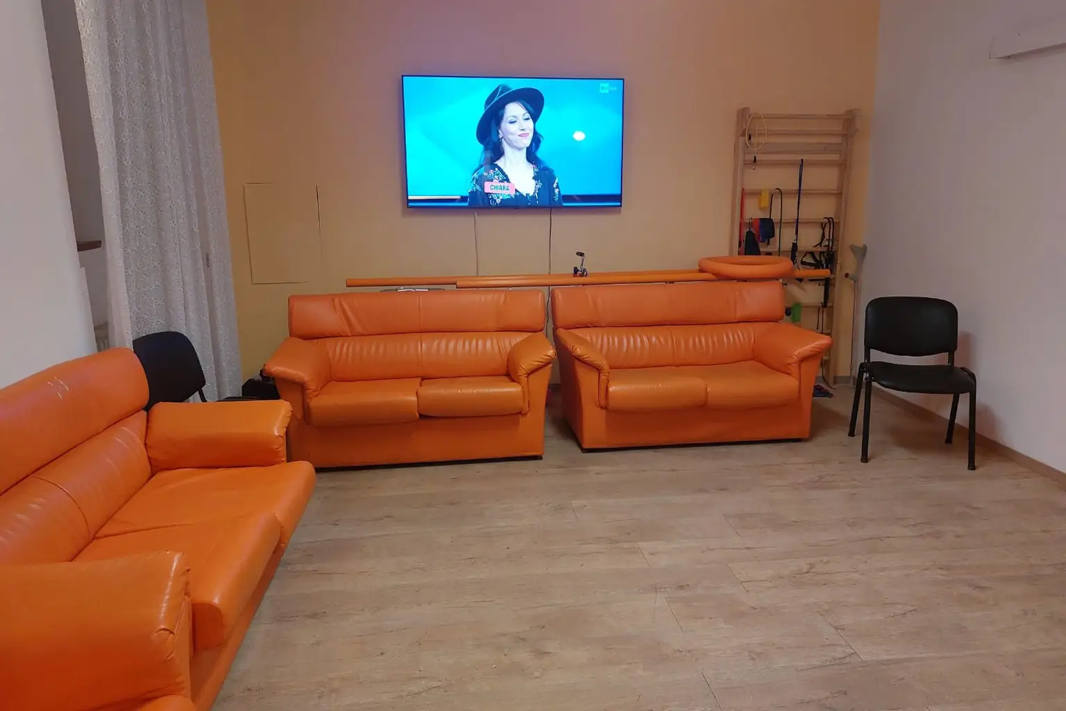 Una stanza comune della struttura, con televisione e divani arancioni.